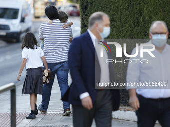 A man carrying his son and daughter during the first day of school on September 10, 2020 in Granada, Spain.  (