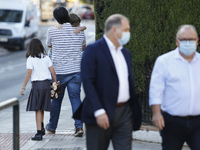 A man carrying his son and daughter during the first day of school on September 10, 2020 in Granada, Spain.  (