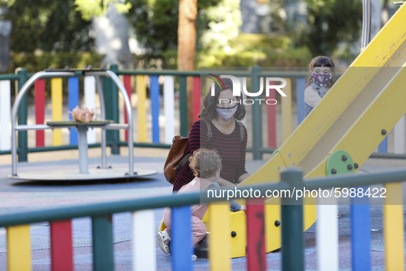 A woman with a facemask is playing with her daughter on a street playground during the first day of school on September 10, 2020 in Granada,...