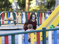 A woman with a facemask is playing with her daughter on a street playground during the first day of school on September 10, 2020 in Granada,...