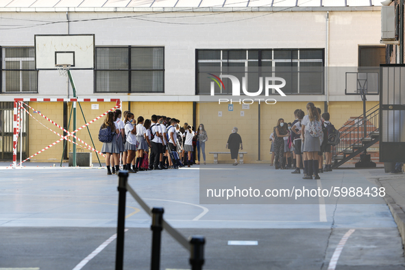 Many kids are forming in a queue waiting to sanitize their hands to enter to an education center during the first day of school on September...