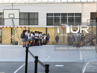 Many kids are forming in a queue waiting to sanitize their hands to enter to an education center during the first day of school on September...