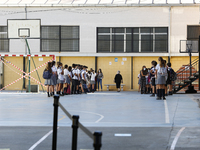 Many kids are forming in a queue waiting to sanitize their hands to enter to an education center during the first day of school on September...