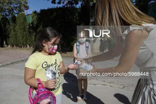 A teacher cleans a student's hands with a hand sanitiser before entering to class during the first day of school on September 10, 2020 in Gr...