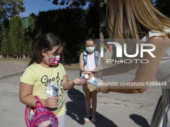 A teacher cleans a student's hands with a hand sanitiser before entering to class during the first day of school on September 10, 2020 in Gr...