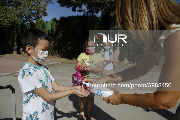 A teacher cleans a student's hands with a hand sanitiser before entering to class during the first day of school on September 10, 2020 in Gr...