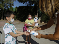 A teacher cleans a student's hands with a hand sanitiser before entering to class during the first day of school on September 10, 2020 in Gr...