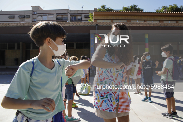 A teacher and a student bumping elbows before entering to class during the first day of school on September 10, 2020 in Granada, Spain.  