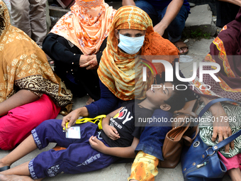 A child sleeping in his mother's lap during garments workers of Dragon Group stage a demonstration in front of Department of Labor building...