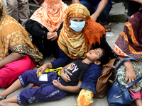 A child sleeping in his mother's lap during garments workers of Dragon Group stage a demonstration in front of Department of Labor building...