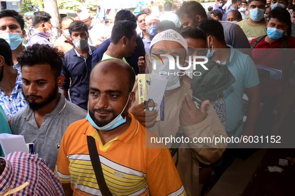 Bangladeshi migrant workers who work in Saudi Arabia gather in front of the Biman Bangladesh Airlines office to collect air tickets to go ba...