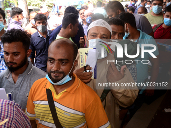 Bangladeshi migrant workers who work in Saudi Arabia gather in front of the Biman Bangladesh Airlines office to collect air tickets to go ba...