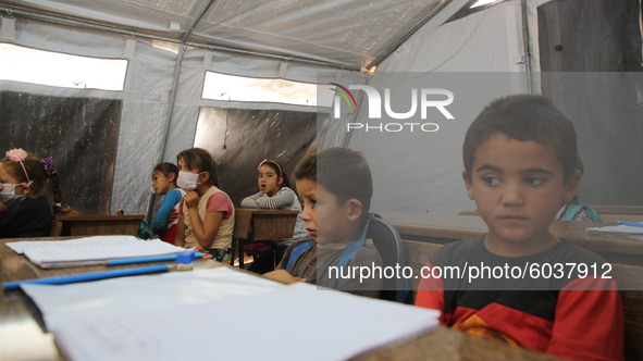 Syrian students wearing protective masks sit on their seats during the first day of the school year in a camp for displaced people near the...