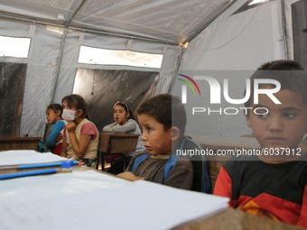 Syrian students wearing protective masks sit on their seats during the first day of the school year in a camp for displaced people near the...