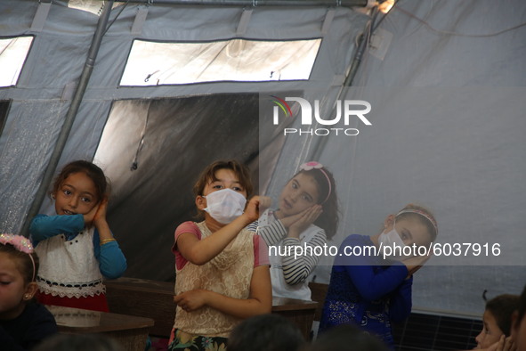 Syrian students wearing protective masks sit on their seats during the first day of the school year in a camp for displaced people near the...