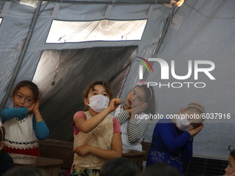 Syrian students wearing protective masks sit on their seats during the first day of the school year in a camp for displaced people near the...