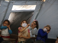 Syrian students wearing protective masks sit on their seats during the first day of the school year in a camp for displaced people near the...