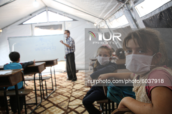 Syrian students wearing protective masks sit on their seats during the first day of the school year in a camp for displaced people near the...