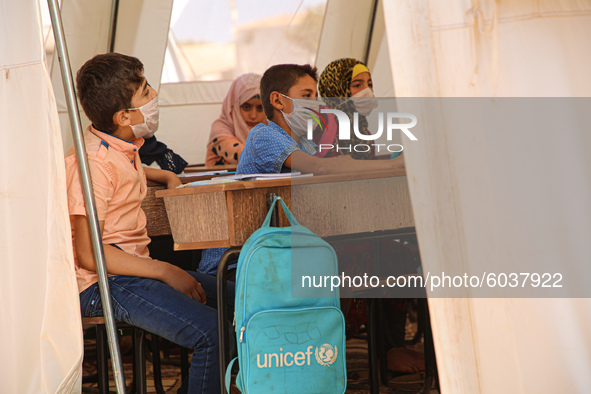 Syrian students wearing protective masks sit on their seats during the first day of the school year in a camp for displaced people near the...