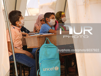 Syrian students wearing protective masks sit on their seats during the first day of the school year in a camp for displaced people near the...