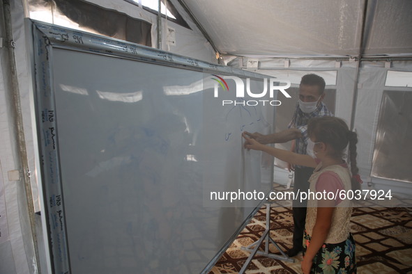 Syrian students wearing protective masks sit on their seats during the first day of the school year in a camp for displaced people near the...