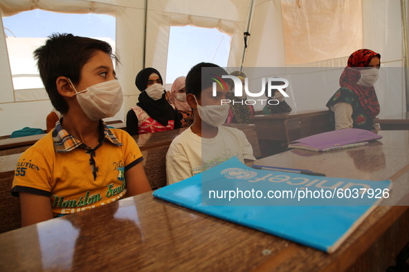 Syrian students wearing protective masks sit on their seats during the first day of the school year in a camp for displaced people near the...