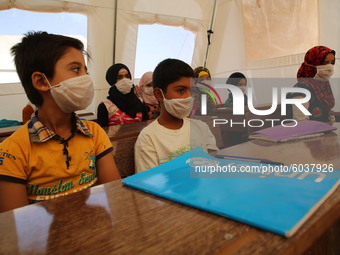 Syrian students wearing protective masks sit on their seats during the first day of the school year in a camp for displaced people near the...