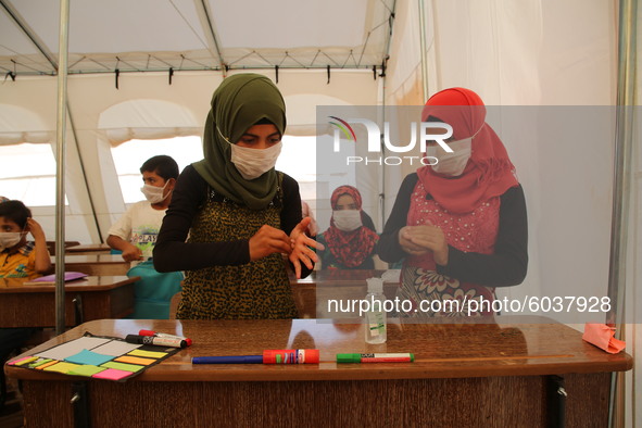 Syrian students wearing protective masks sit on their seats during the first day of the school year in a camp for displaced people near the...