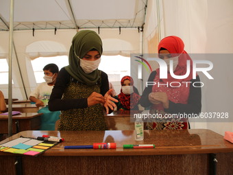 Syrian students wearing protective masks sit on their seats during the first day of the school year in a camp for displaced people near the...