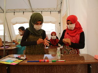 Syrian students wearing protective masks sit on their seats during the first day of the school year in a camp for displaced people near the...