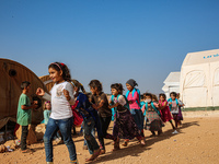 Syrian students play in front of their school tent on the first day of the new school year near the city of Maarat Misreen in Idlib countrys...