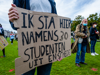 A male student is holding a placard in representation of other students during the students protest for more physical attendance classes, in...