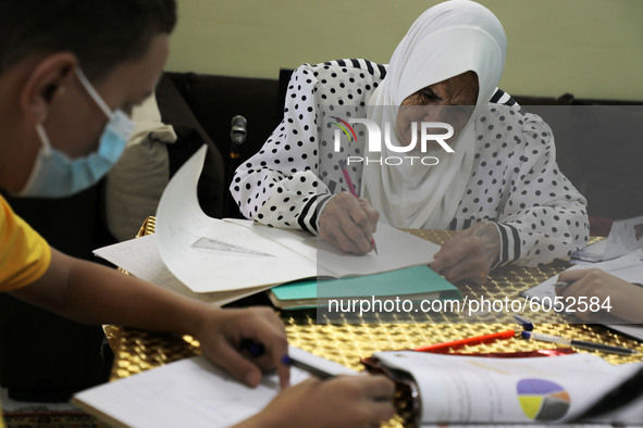 Palestinian teacher Ekram el-astal, 80, teaches her neighbours' students an Maths language lesson as schools are shut due to the coronavirus...