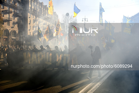 Veterans, activists and supporters of Ukraine's nationalist movements light flares during a procession to mark the Defender of Ukraine Day a...