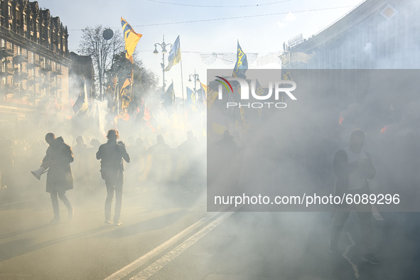 Veterans, activists and supporters of Ukraine's nationalist movements light flares during a procession to mark the Defender of Ukraine Day a...