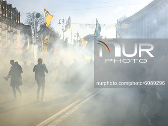 Veterans, activists and supporters of Ukraine's nationalist movements light flares during a procession to mark the Defender of Ukraine Day a...