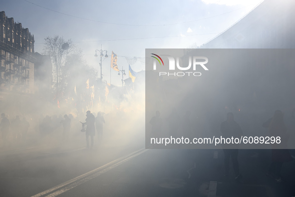 Veterans, activists and supporters of Ukraine's nationalist movements light flares during a procession to mark the Defender of Ukraine Day a...