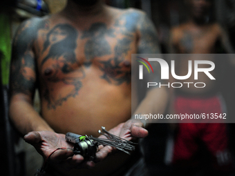 Go to http://nurphoto.com/reportages/ to see more - An inmate shows the tattoo maker that they are using, made of homemade materials such as...