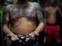 Go to http://nurphoto.com/reportages/ to see more - An inmate shows the tattoo maker that they are using, made of homemade materials such as...