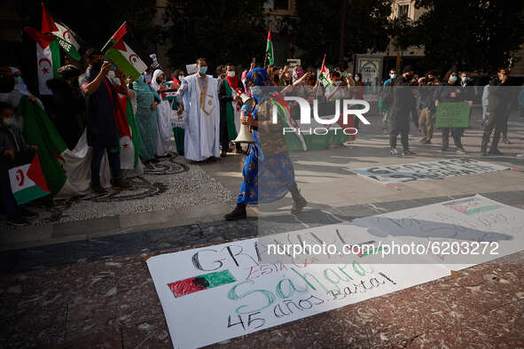 A woman with a megaphone passes a placard that says' Granada is with the Sahara. 45 years. Enough!' during a demonstration to demand the end...
