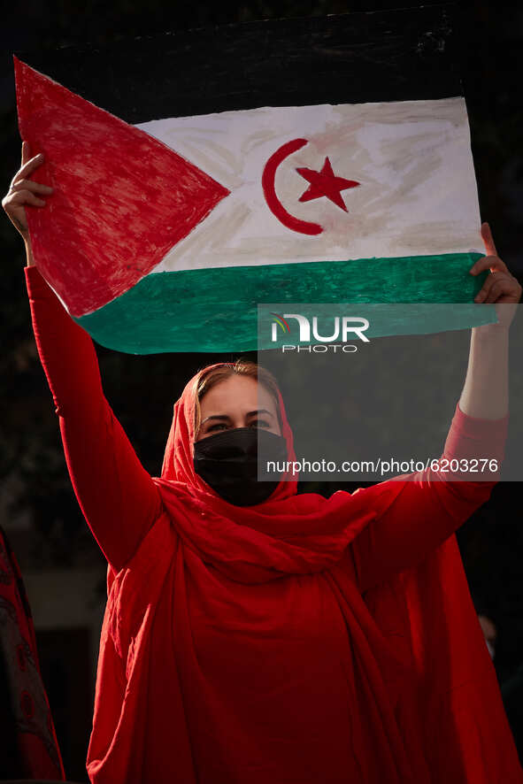 A woman dressed in Malahfa and wearing a face mask carries a Saharan flag during a demonstration to demand the end of Morocco's occupation i...