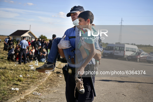 A Croatian border policeman carries a migrant boy to the transfer camp in Opatovac near border crossing point between Serbia and Croatia. Se...