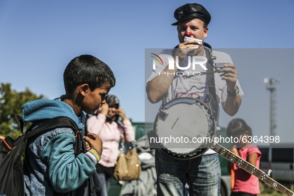 A volunteer entertains migrant children waiting to enter the transfer camp in Opatovac near border crossing point between Serbia and Croatia...