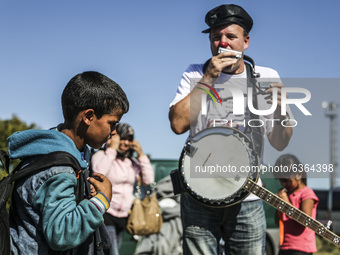 A volunteer entertains migrant children waiting to enter the transfer camp in Opatovac near border crossing point between Serbia and Croatia...