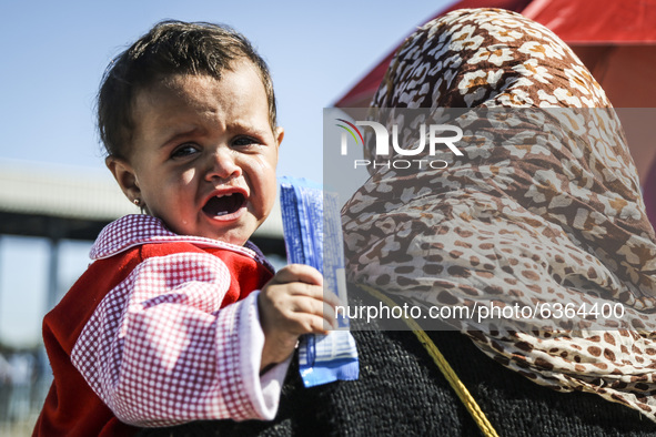 A igrant womman carries a crying baby while waiting to enter the transfer camp in Opatovac near border crossing point between Serbia and Cro...