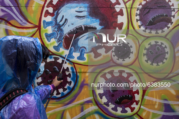 A man spray disinfectan to the mural. Mural Covid19 in Tangerang, Banten, Indonesia, on 26 January 2021. Indonesia reach out to 1 million of...