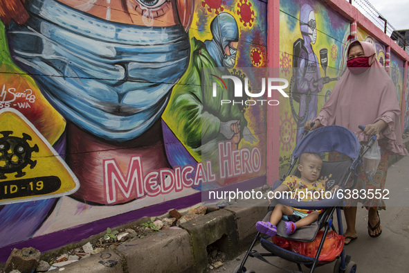 A woman passing by the mural in Tangerang, Banten, Indonesia, 26 January 2021. Indonesia reach out to 1 million of Covid19 positive case wit...