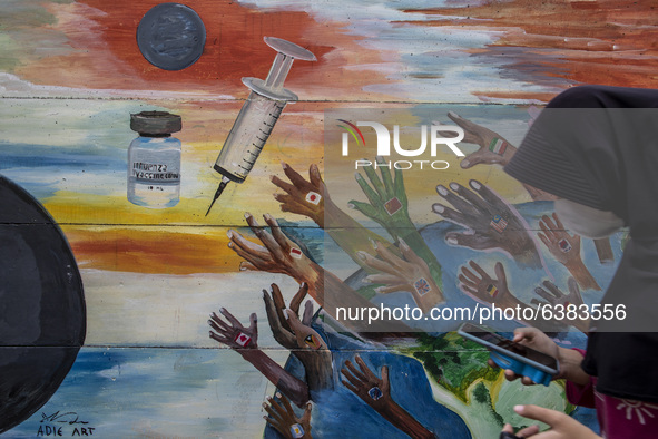 A woman passing by the mural in Tangerang, Banten, Indonesia, 26 January 2021. Indonesia reach out to 1 million of Covid19 positive case wit...