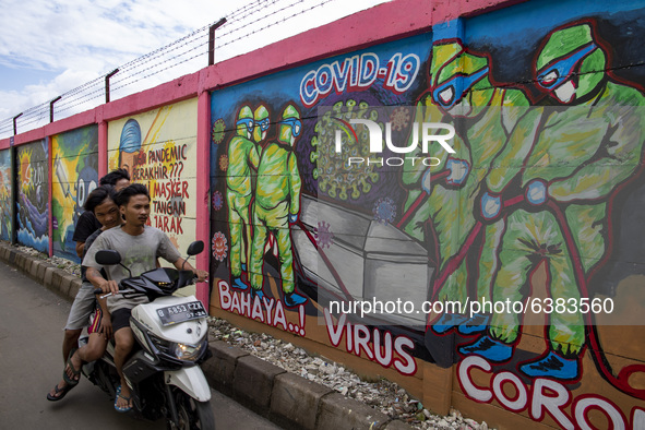 Thrree young men without mask passing by the mural in Tangerang, Banten, Indonesia, on 26 January 2021. Indonesia reach out to 1 million of...