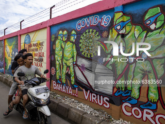 Thrree young men without mask passing by the mural in Tangerang, Banten, Indonesia, on 26 January 2021. Indonesia reach out to 1 million of...